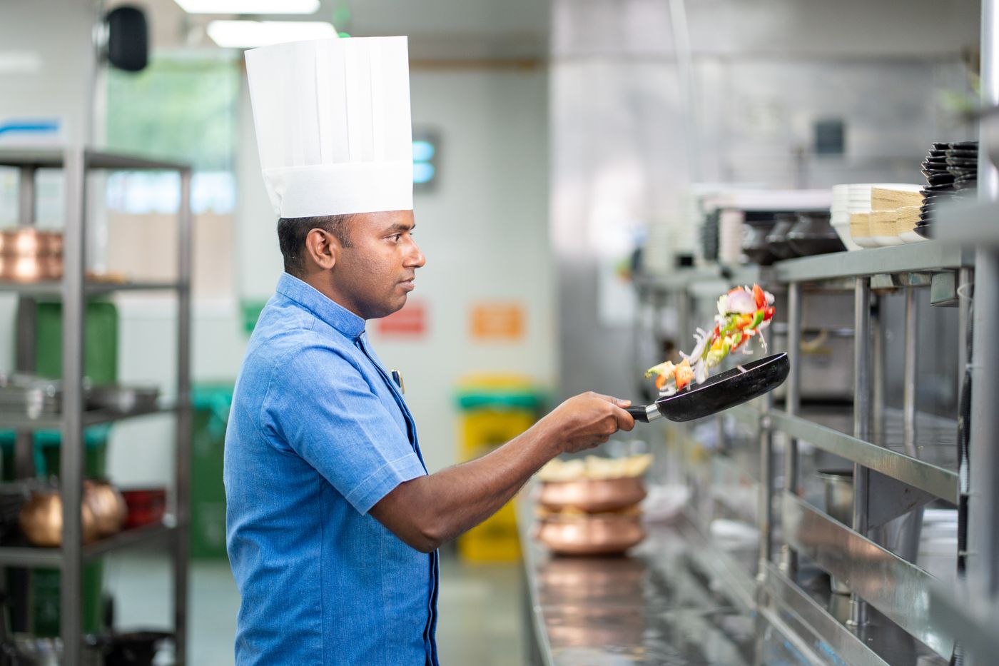 A chef at a stainless-steel station in a commercial kitchen