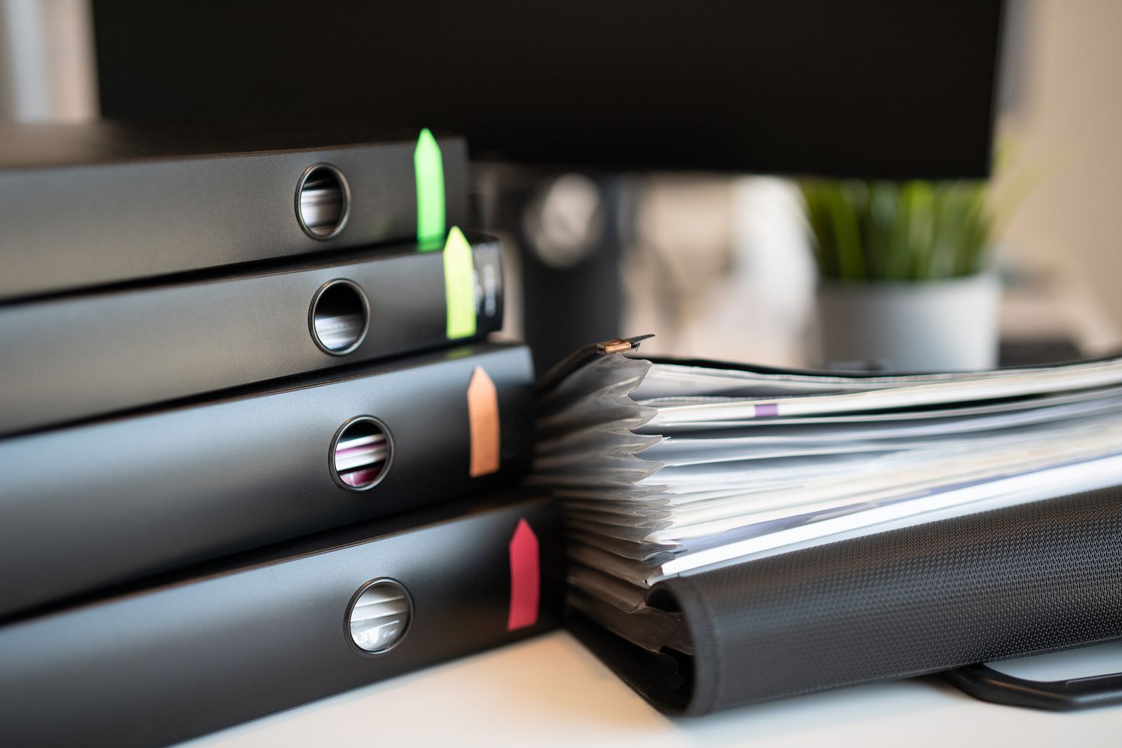 Organised ring binders with coloured index tabs stacked beside a file of records
