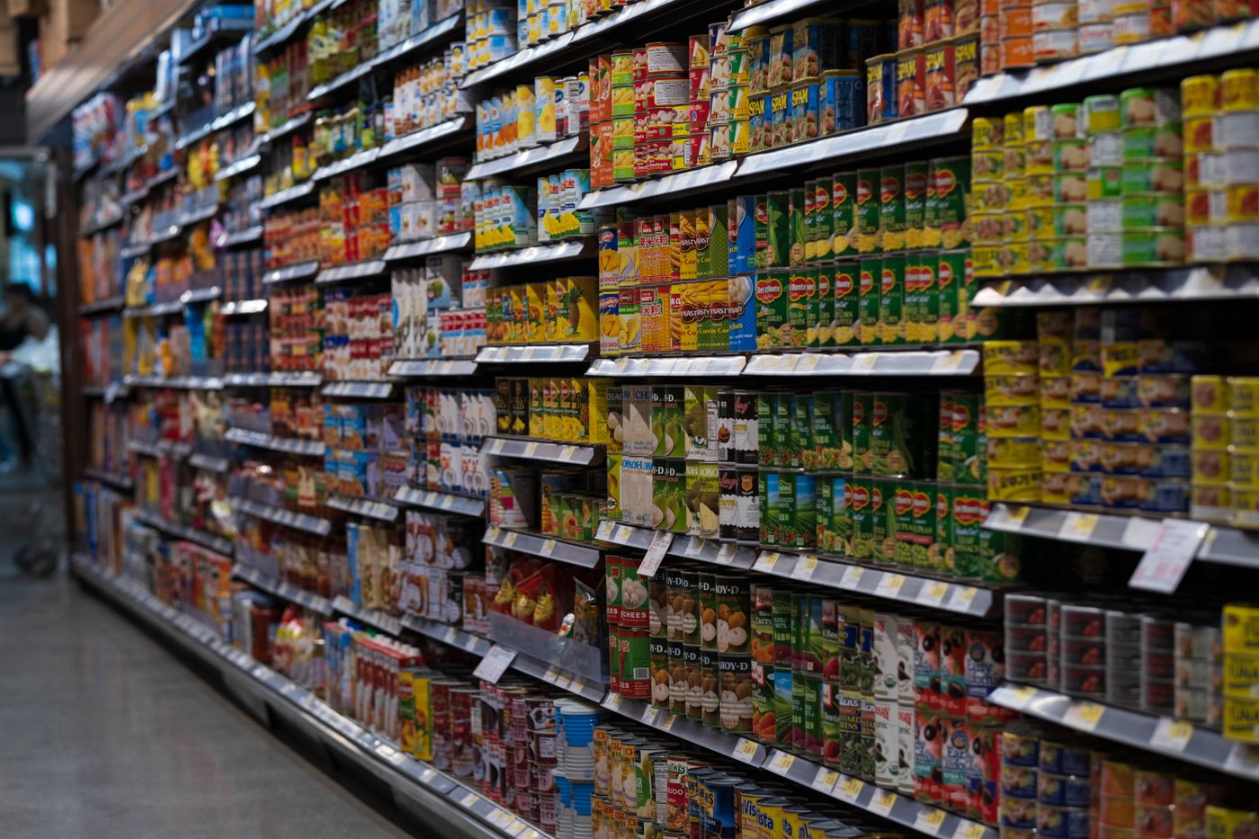 A supermarket aisle with shelves stocked with packaged and canned food